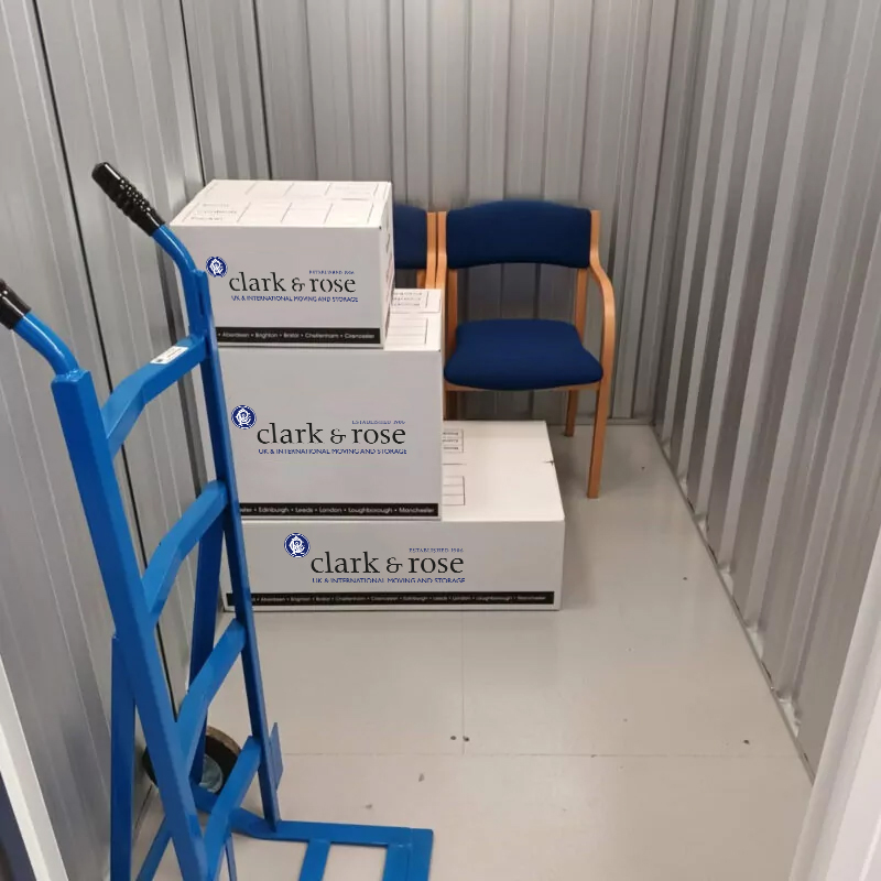 Boxes and chairs in a storage unit to demonstrate the size of the unit