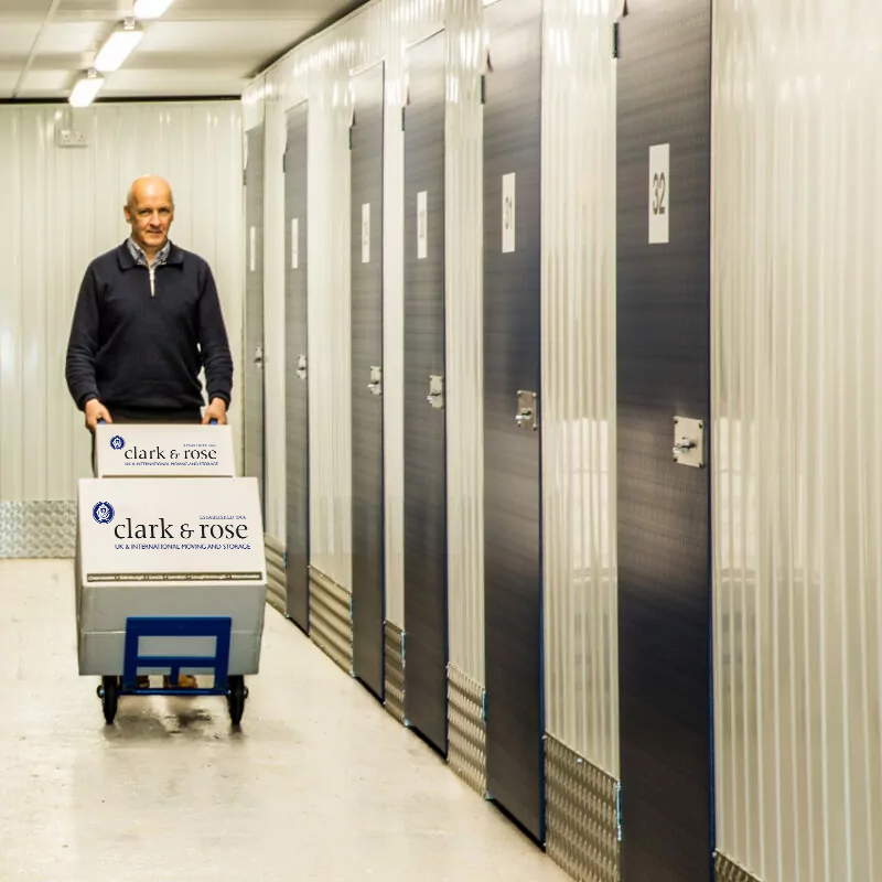 Man using a trolley to move boxes into indoor storage units
